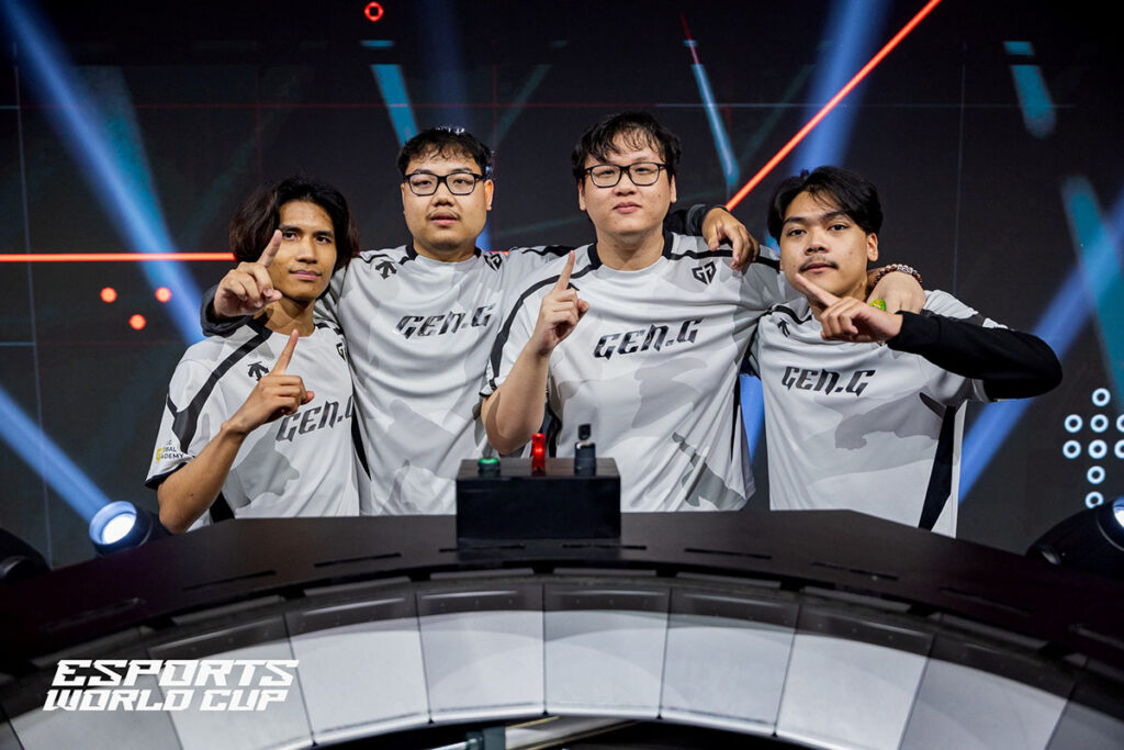 Four Gen.G players in white camouflage Gen.G jerseys posing arm-in-arm behind a podium on a lit esports stage at the Esports World Cup.