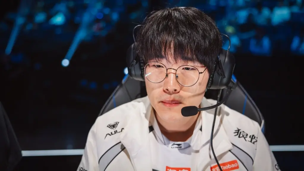 Close-up of a League of Legends pro player in a white LPL jersey with headset and microphone, seated at his station during the Worlds 2026 Swiss Stage.